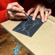 Load image into Gallery viewer, A linocut student carves two birds designed and taught by Fabia