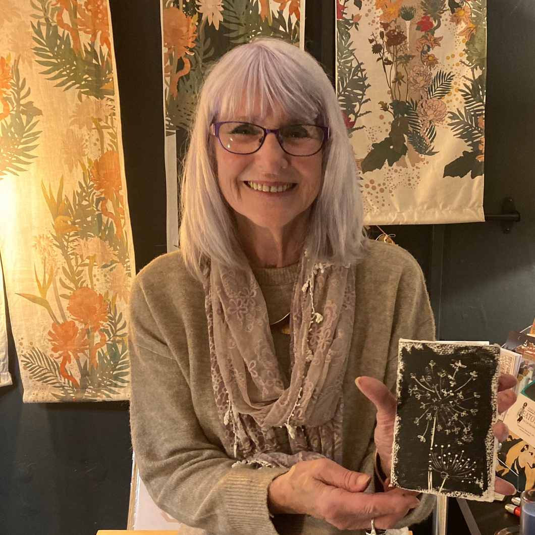 A student proudly shows their first linocut printed on a card at Fabias workshop