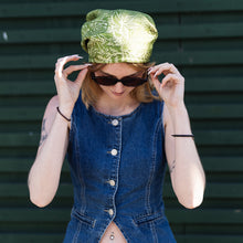 Load image into Gallery viewer, A stylish young woman, wearing a green linocut patterned silk scarf as a bandana adjusts her sunglasses wearing a denim vest against a dark background
